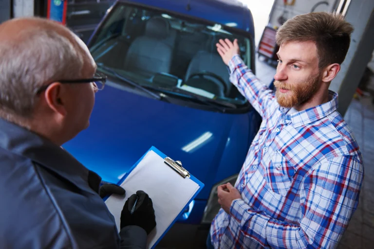 A photo of a Ford Ranger pickup truck being serviced at a dealership, with mechanics inspecting the vehicle.